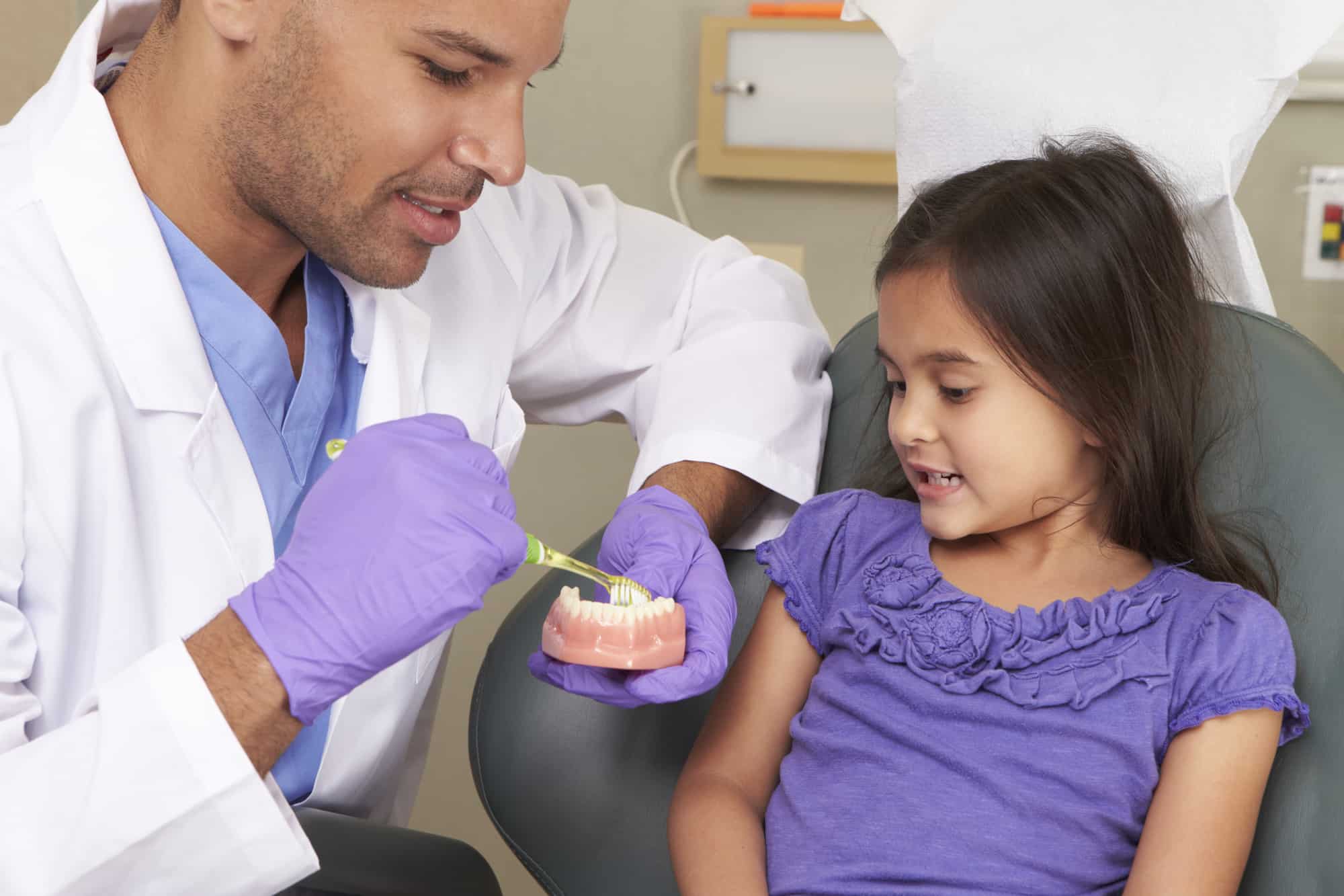 dentist showing child a model of teeth during super seven checkup